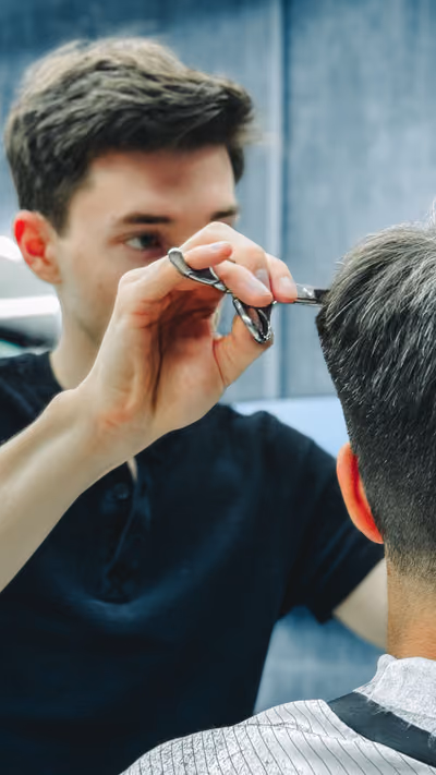 Barbero cortando el cabello a un cliente en una barbería moderna